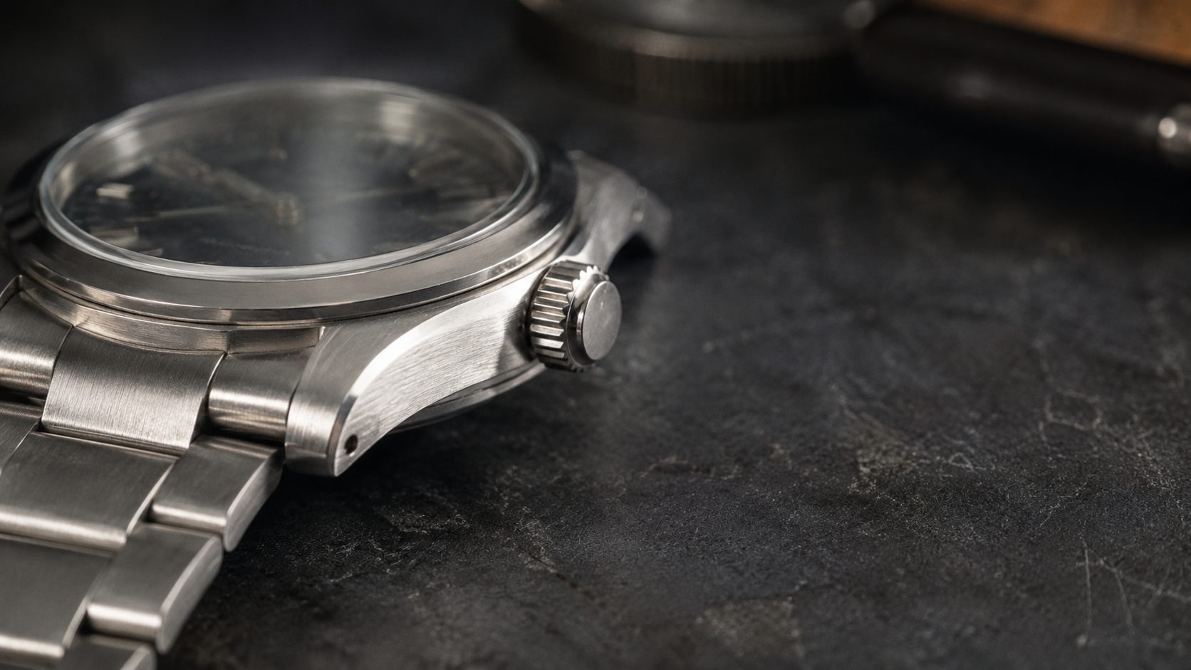 Close-up of a stainless steel luxury watch on a dark surface